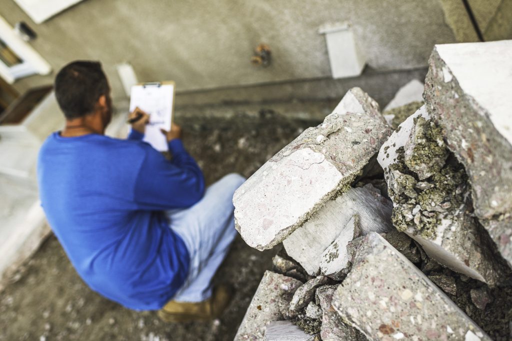 Male housing inspector taking notes on problem area of home