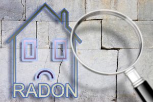 The danger of radon gas in our homes - concept image with an outline of a small house with radon text against a cracked stone wall with a magnifying glass