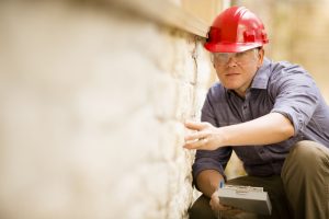 Inspector or blue collar worker examines building wall outdoors.