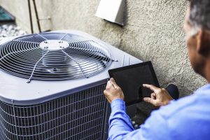 Maintenance engineer using digital tablet to inspect air conditioning unit