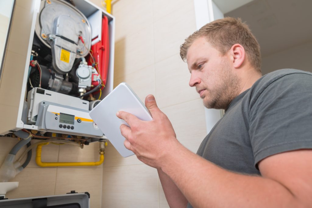 A home inspector completes a home inspection for a client on the gas line in the home